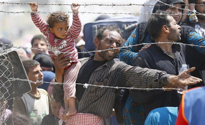 A Syrian refugee reacts as he waits behind border fences to cross into Turkey at Akcakale border gate in Sanliurfa province, Turkey, June 15, 2015. REUTERS/Umit Bektas   SEARCH "YEAREND 2015: MIGRANT CRISIS" FOR ALL 55 PICTURES